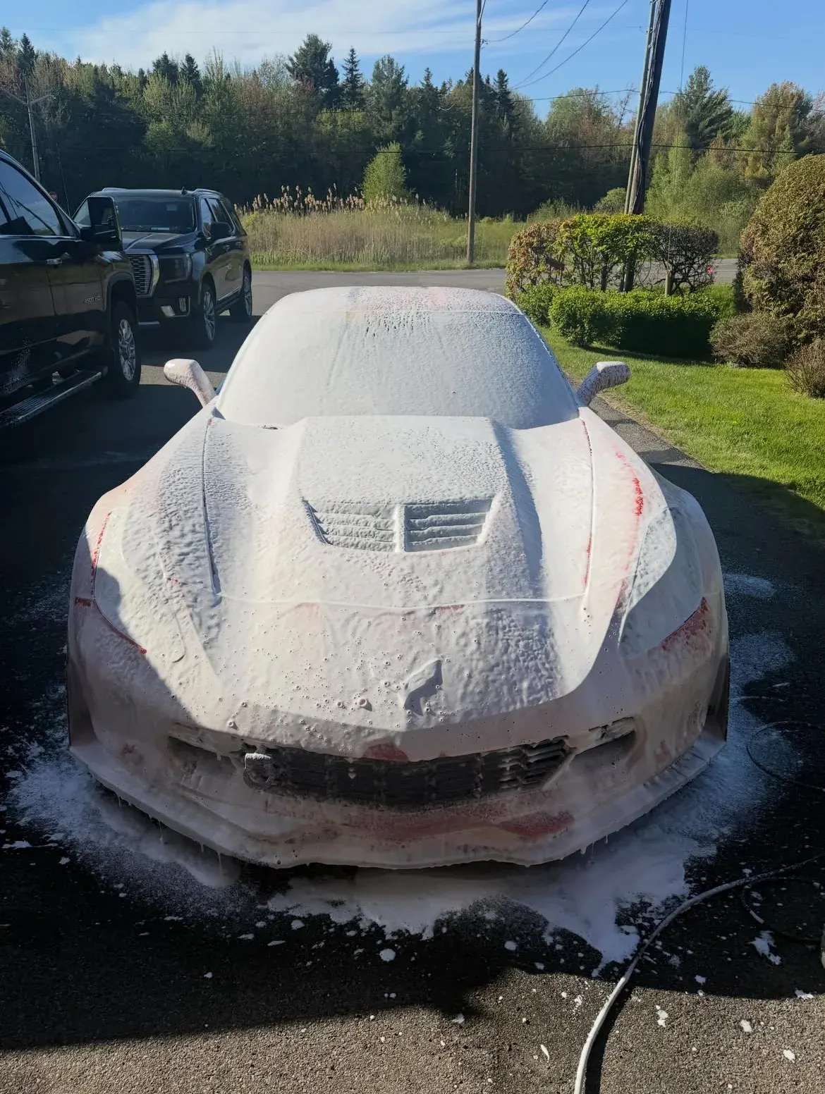 Detailer foam-washing a sports car before hand detailing